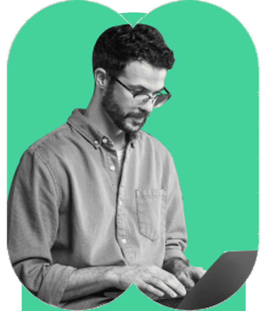 Male university student with glasses and beard working on laptop popping out of wide emerald green arch